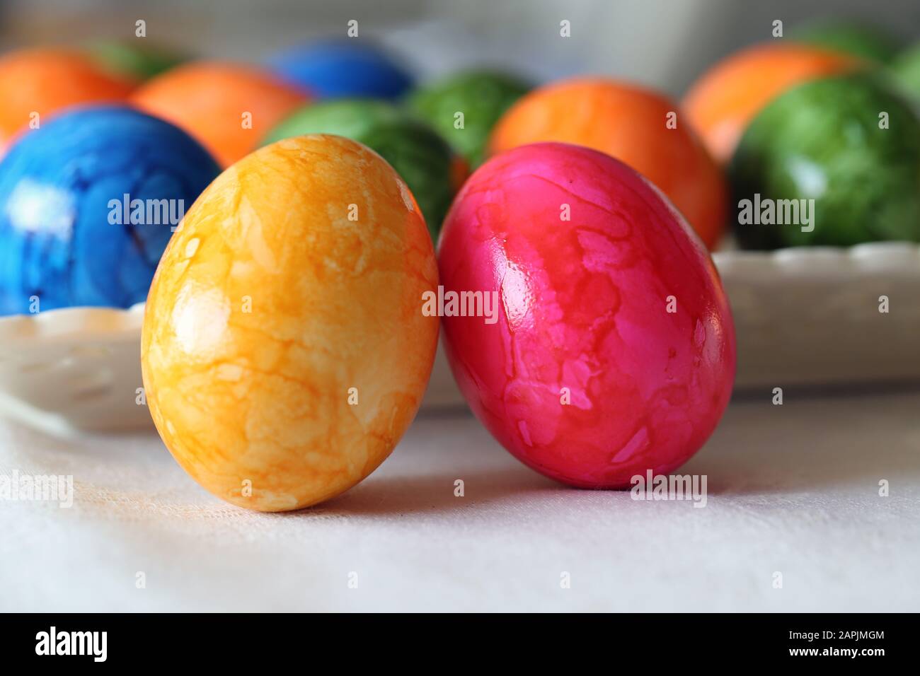 Bunte und fröhliche Osterdekorationen auf einem Tisch. Nahfarbenbild von mehreren bemalten Ostereiern mit fröhlichen und lebendigen Farben. Stockfoto