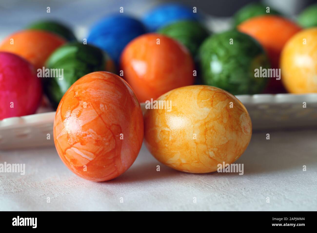 Bunte und fröhliche Osterdekorationen auf einem Tisch. Nahfarbenbild von mehreren bemalten Ostereiern mit fröhlichen und lebendigen Farben. Stockfoto