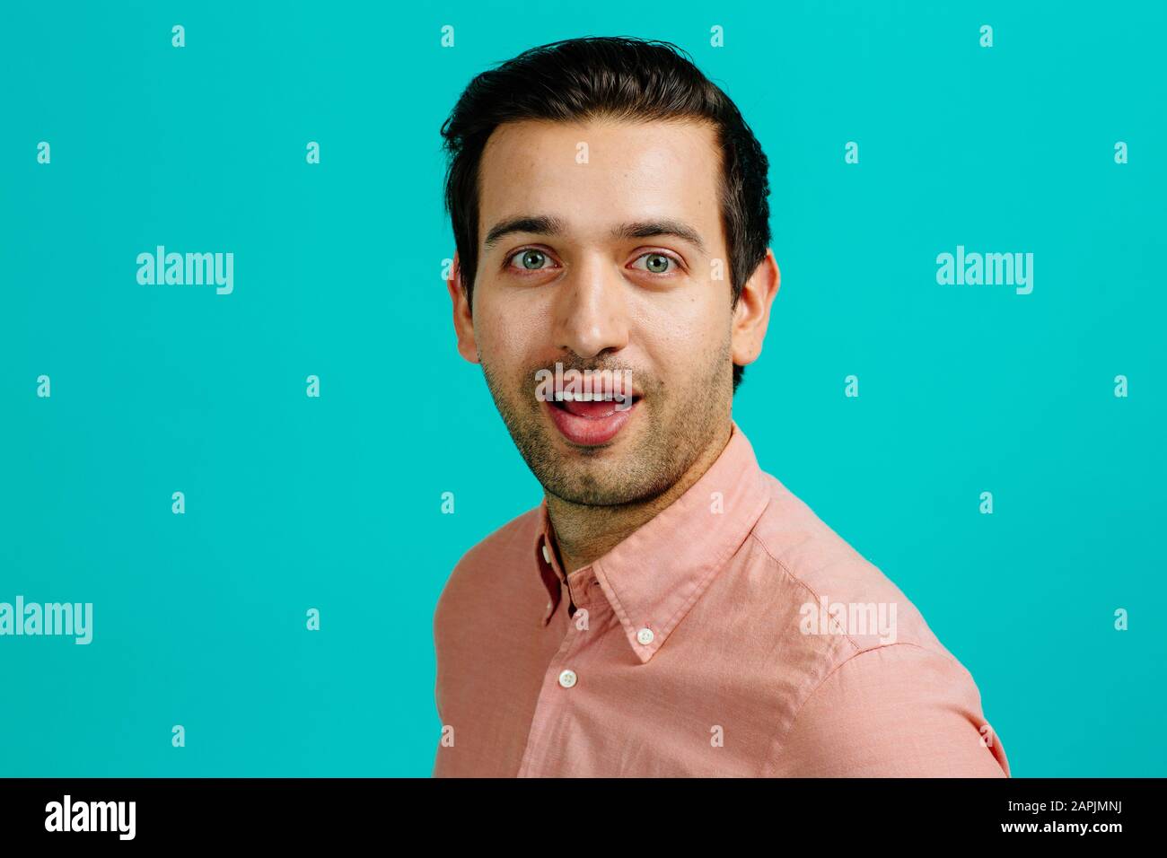 Porträt eines jungen erwachsenen Mannes lächelnd, isoliert auf blauem Studiohintergrund Stockfoto