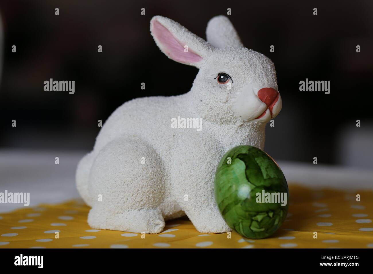 Bunte und fröhliche Osterdekorationen auf einem Tisch. Nahfarbenbild einer keramisch weißen Osterhase und bunt bemalten Ostereiern. Stockfoto