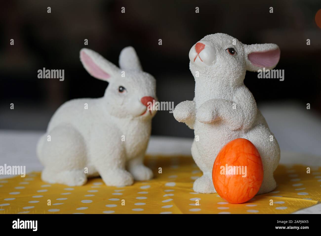 Bunte und fröhliche Osterdekorationen auf einem Tisch. Nahfarbenbild von zwei keramischen Osterhasen und bunt bemalten Ostereiern. Stockfoto