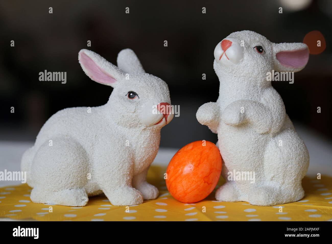 Bunte und fröhliche Osterdekorationen auf einem Tisch. Nahfarbenbild von zwei keramischen Osterhasen und bunt bemalten Ostereiern. Stockfoto