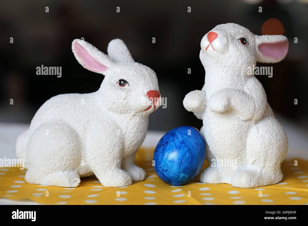 Bunte und fröhliche Osterdekorationen auf einem Tisch. Nahfarbenbild von zwei keramischen Osterhasen und bunt bemalten Ostereiern. Stockfoto