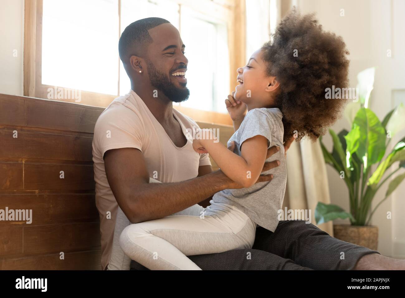 Afrikanischer Vater kitzelt kleine Tochterfamilie, die Spaß im Haus hat Stockfoto