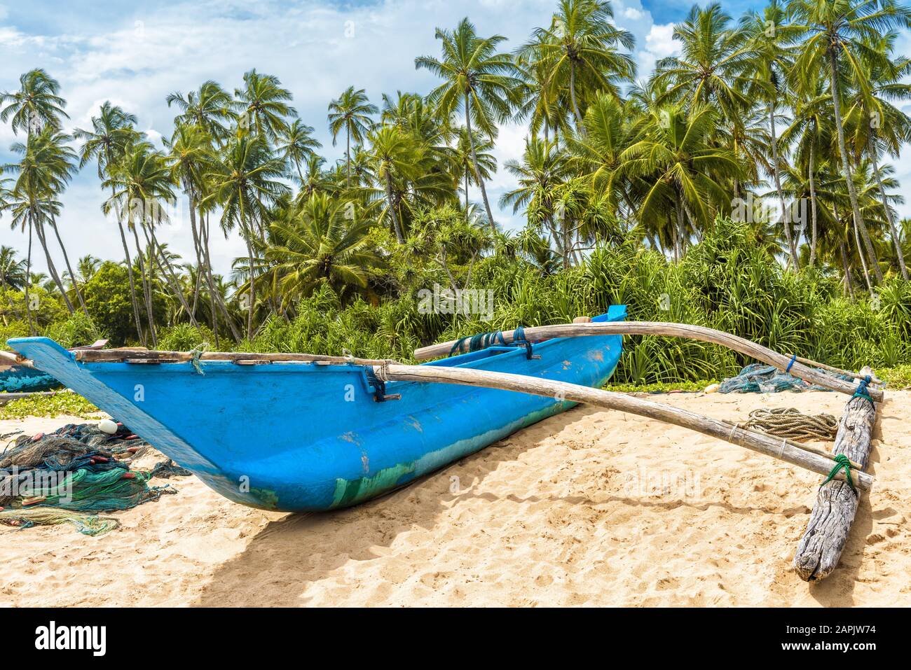 Altes traditionelles Fischerboot am Strand in Sri Lanka. Blick auf den Strand mit Kokospalmen. Stockfoto