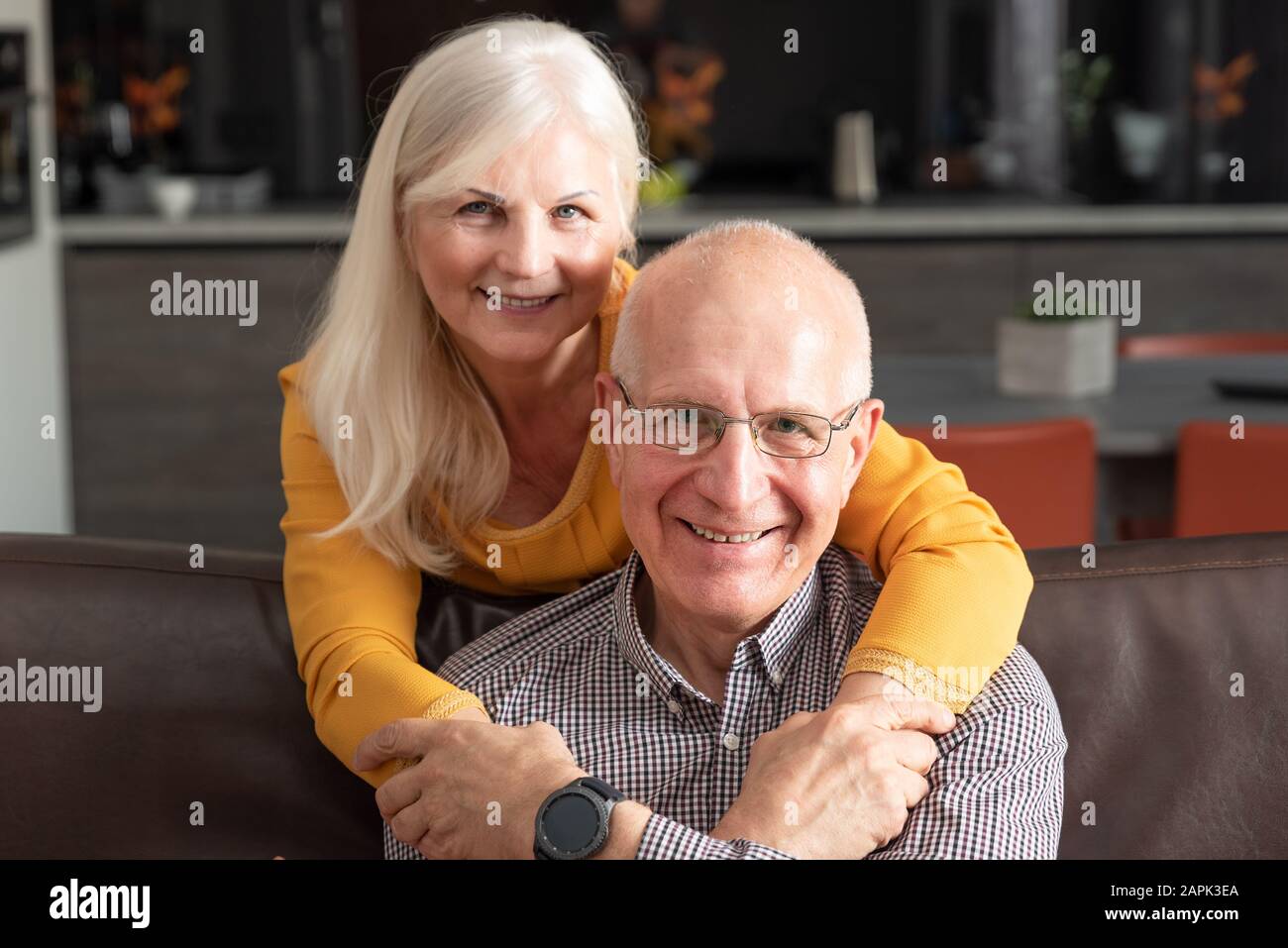 Fröhliche, romantische senior Paar umarmen beim Sitzen auf dem Sofa zu Hause Stockfoto