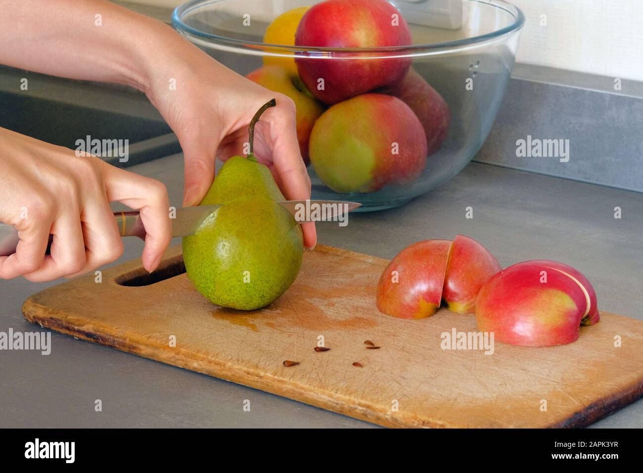Kochkonzept. Birnen und Äpfel schneiden sich auf Holzplatten auf dem Küchentisch zu Scheiben. Stockfoto