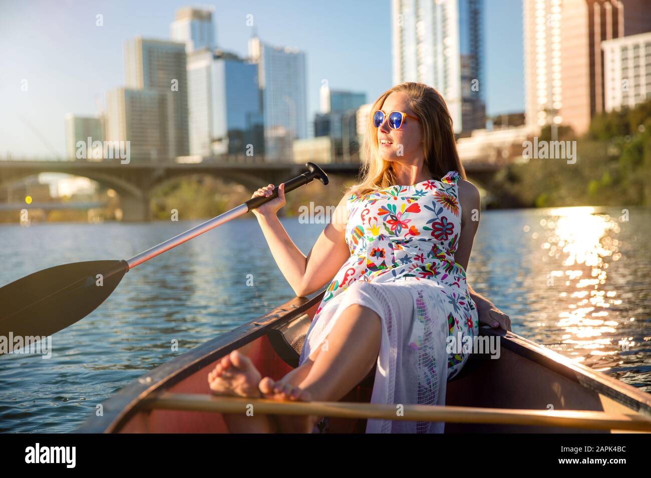 Lustiger Lifestyle-Sommertag in einem Boot auf dem Wasser neben dem Stadtbild der städtischen Skyline, Entspannung, Reisen und Tourismus Stockfoto