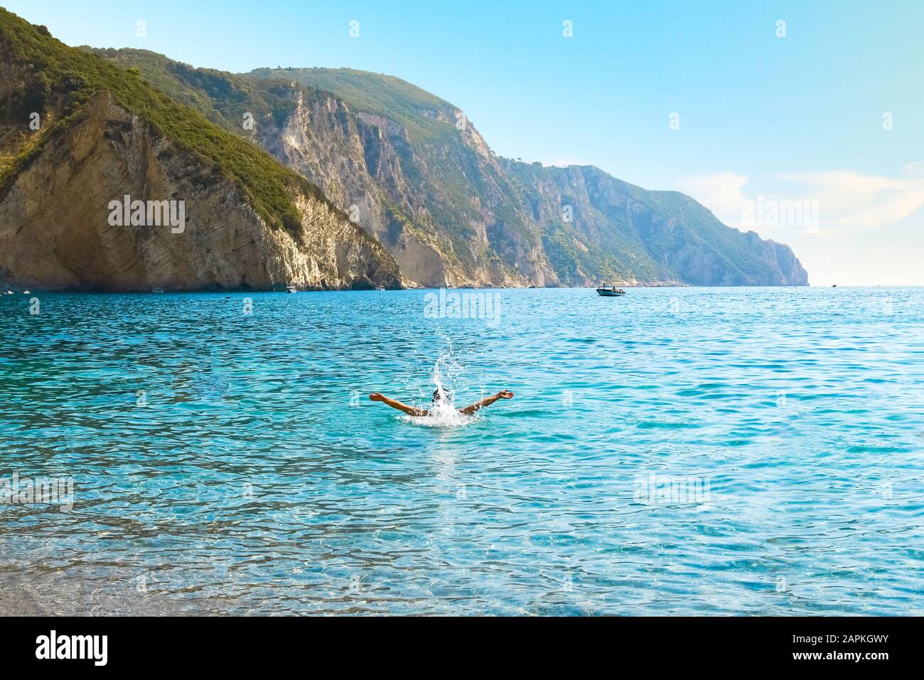 Ein Tourist spielt und spritzt im Meer am Chomi oder Paradise Beach auf der griechischen Insel Korfu. Stockfoto
