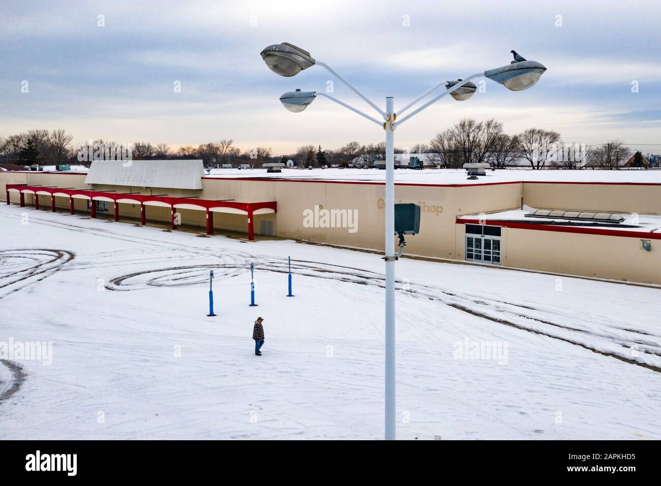 ST Clair Shores, Michigan - EIN Mann läuft über einen leeren Parkplatz an einem geschlossenen Kmart in der Vorstadt von Detroit, einem von vielen großen Kastengeschäften, die geschlossen haben Stockfoto