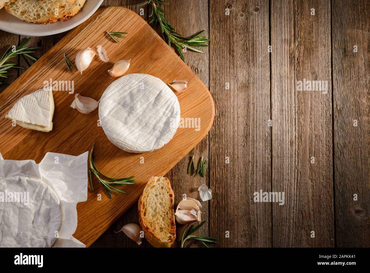 Camembert Käse, Knoblauch, Rosmarin und Brot auf Holzschneidebrett Stockfoto