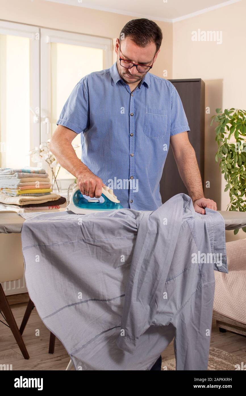Mann beim Bügeln. Die Aufgaben der Männer. Ein formelles Hemd von einem Mann mit einem Bügeleisen bügeln. Stockfoto