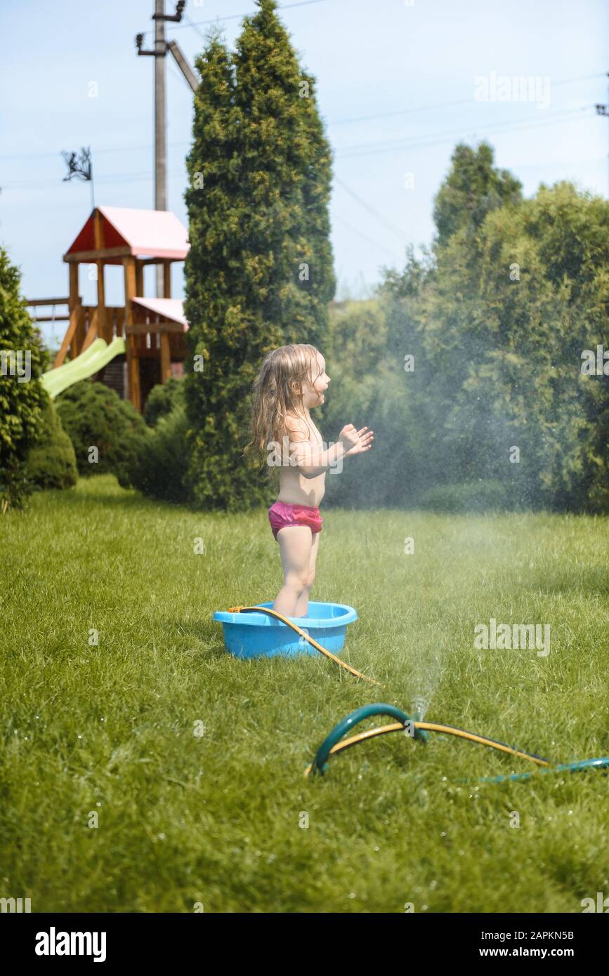 Kleines Mädchen spielt mit Wasser im Hof zu Hause Stockfoto