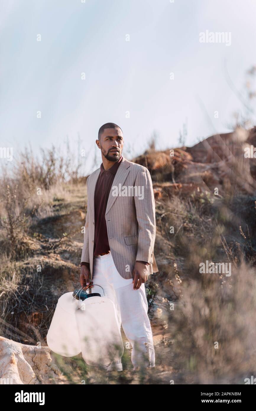 Junger Mann, der leere Dosen auf der Suche nach Wasser in unfruchtbarem Land hält Stockfoto