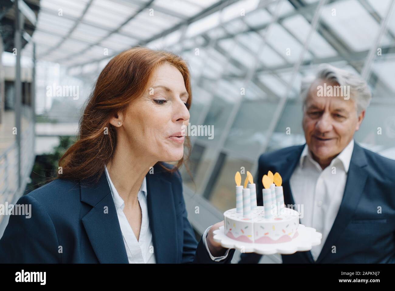 Geschäftsmann und Geschäftsfrau feiern Geburtstag im Amt mit gefälschtem Geburtstagskuchen Stockfoto