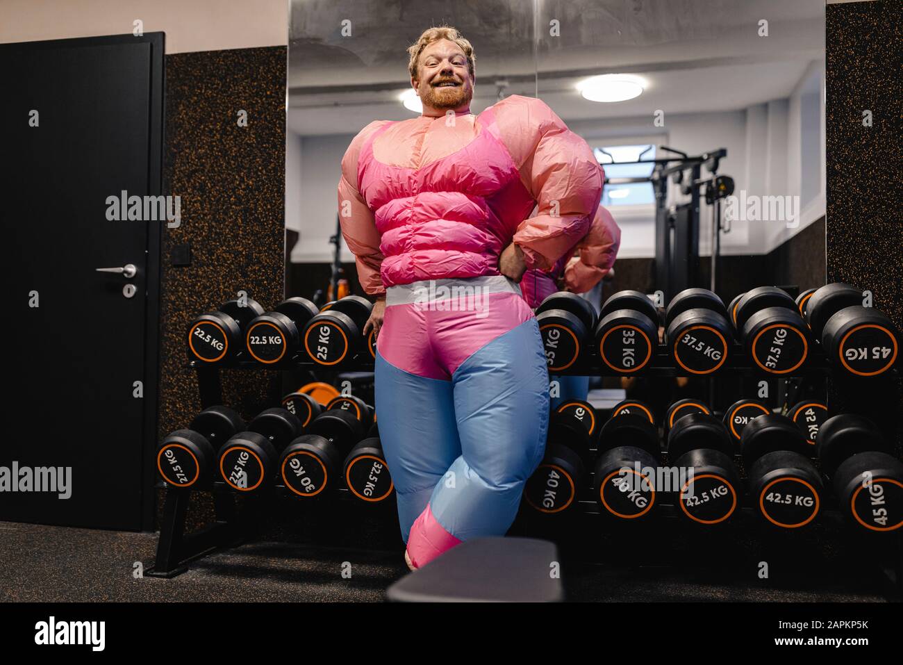 Stolzer Mann, der im Fitnessstudio ein pinkfarbenes Bodybuilder-Kostüm trägt Stockfoto