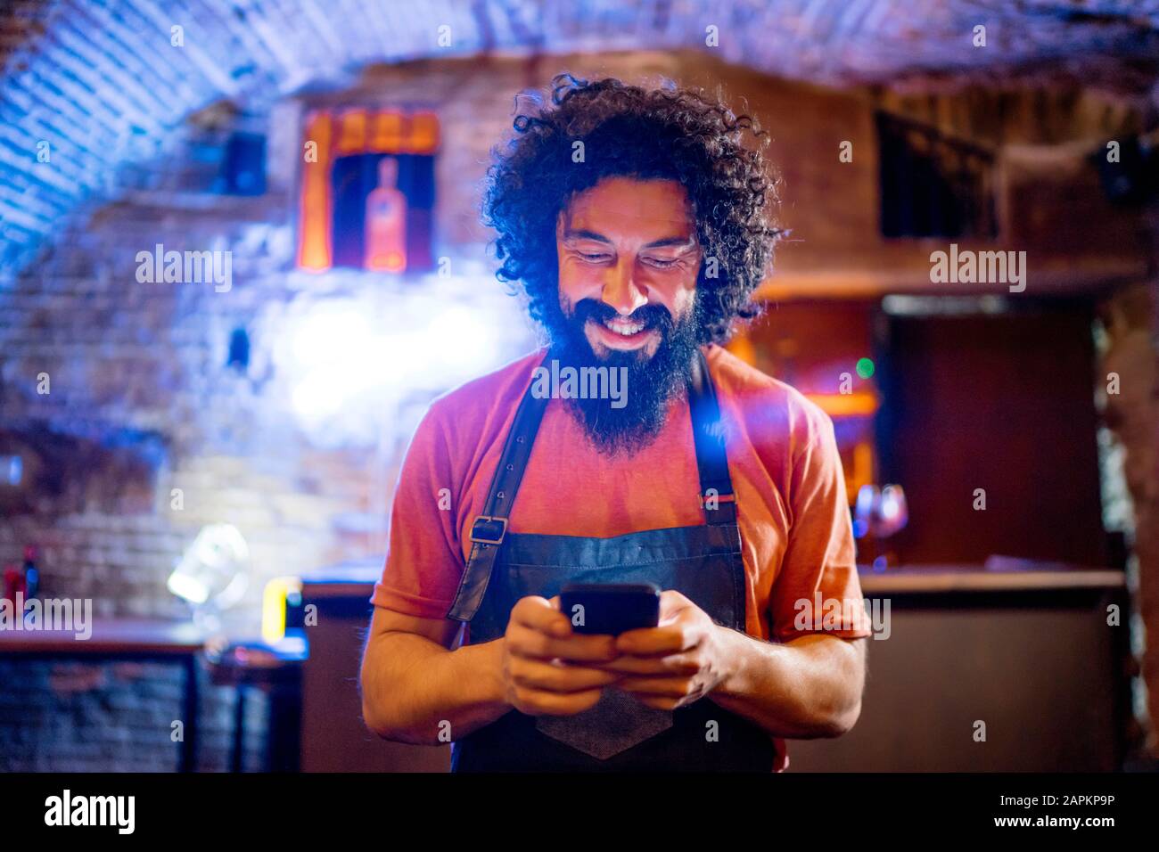 Junger Mann, der in der Bar arbeitet und Smartphone verwendet Stockfoto
