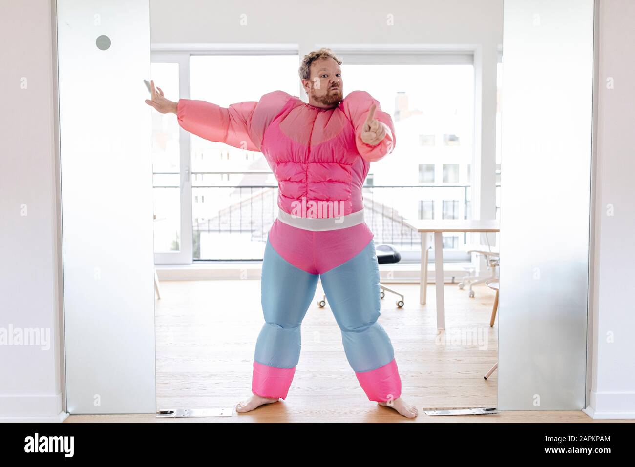 Hüpfer im Büro mit pinkfarbenem Bodybuilder-Kostüm Stockfoto