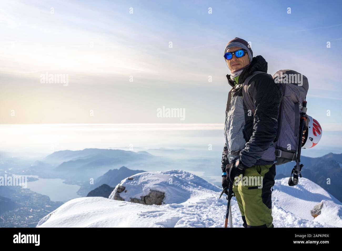 Porträt eines Alpinisten, der auf dem schneebedeckten Berggipfel steht, Orobie Alps, Lecco, Italien Stockfoto