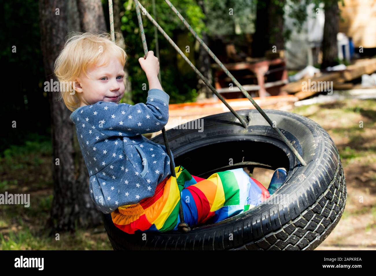 Portrait des kleinen Mädchens, das auf dem Reifenschwenk sitzt Stockfoto