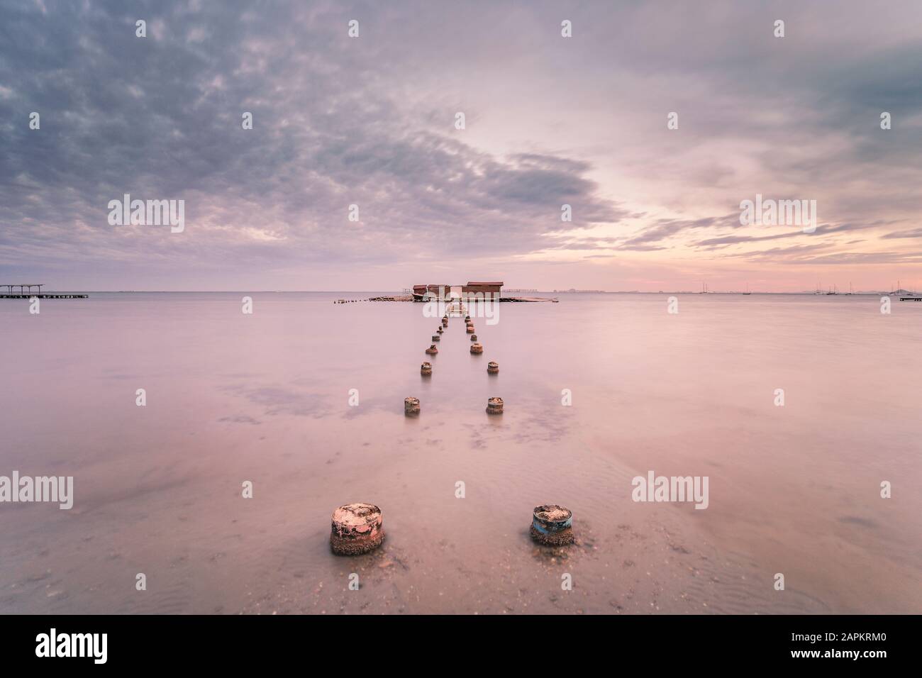 Spanien, Murcia, Santiago de la Ribera, Holzpfosten in ruhiger See bei Sonnenuntergang Stockfoto