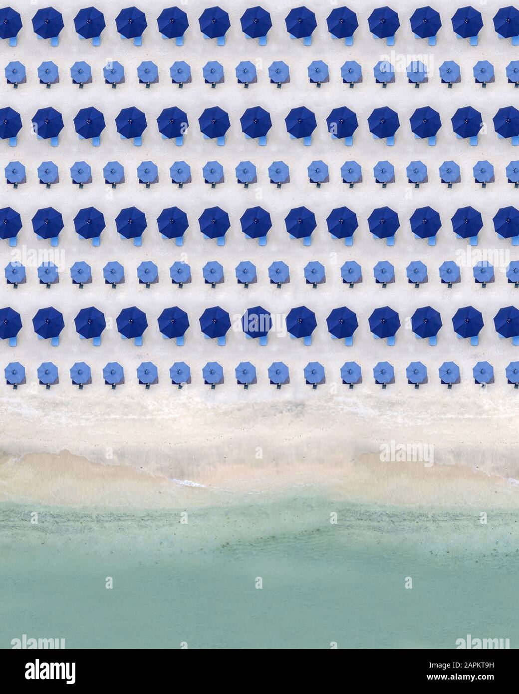 Luftaufnahme von Reihen von blauen Sonnenschirmen entlang sandigen Küstenstrand Stockfoto