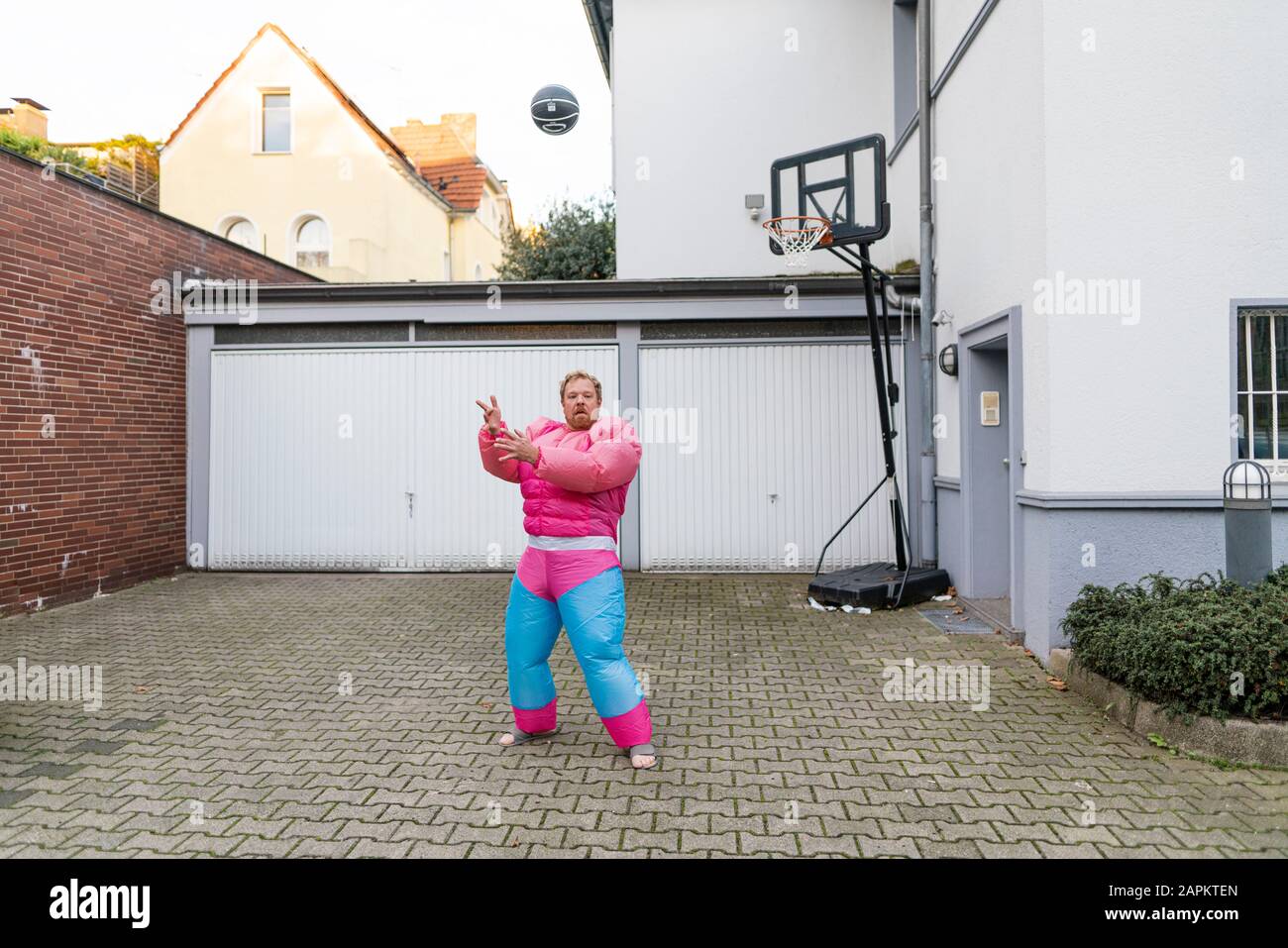 Porträt eines Mannes mit Basketball mit pinkfarbenem Bodybuilder-Kostüm Stockfoto