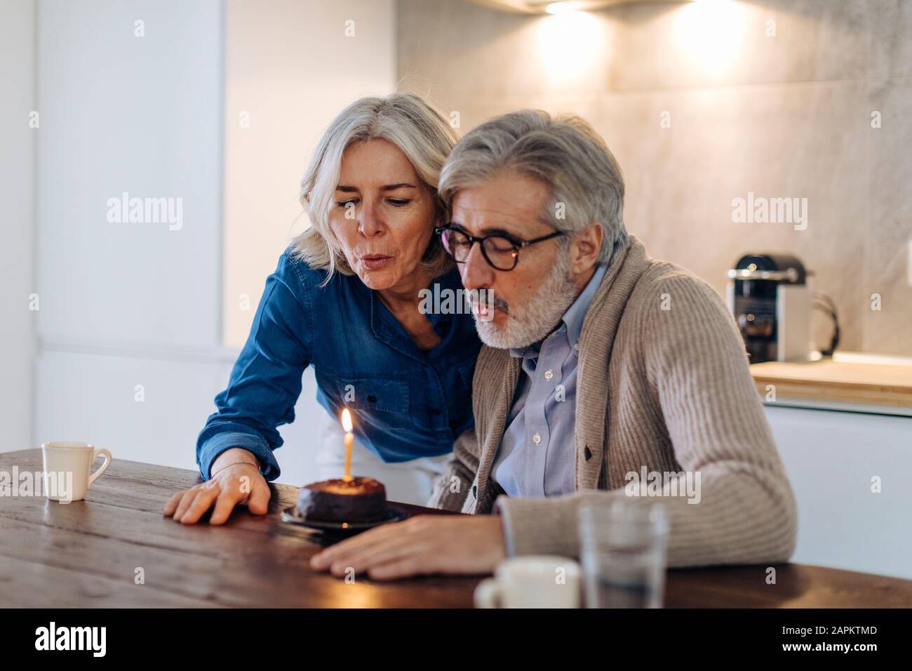 Reifes Paar feiert Geburtstag mit Kuchen in der Küche zu Hause Stockfoto