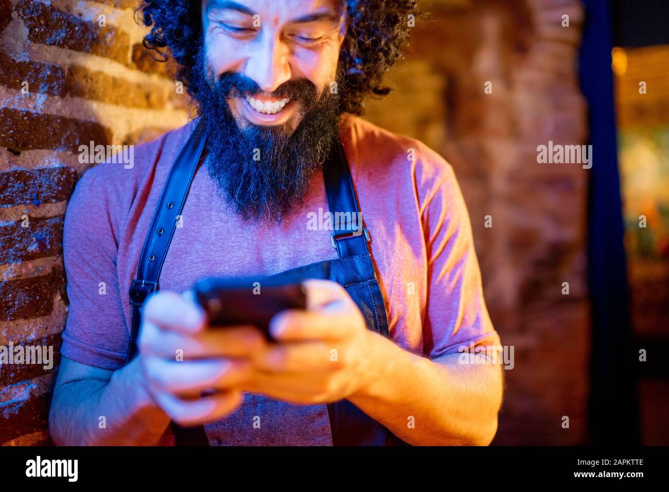 Junger Mann, der in der Bar arbeitet und Smartphone verwendet Stockfoto