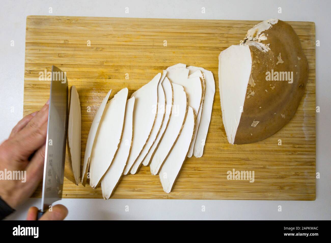 Man hackt mit der Hand Birkenpolypore auf Holzbrett Stockfoto