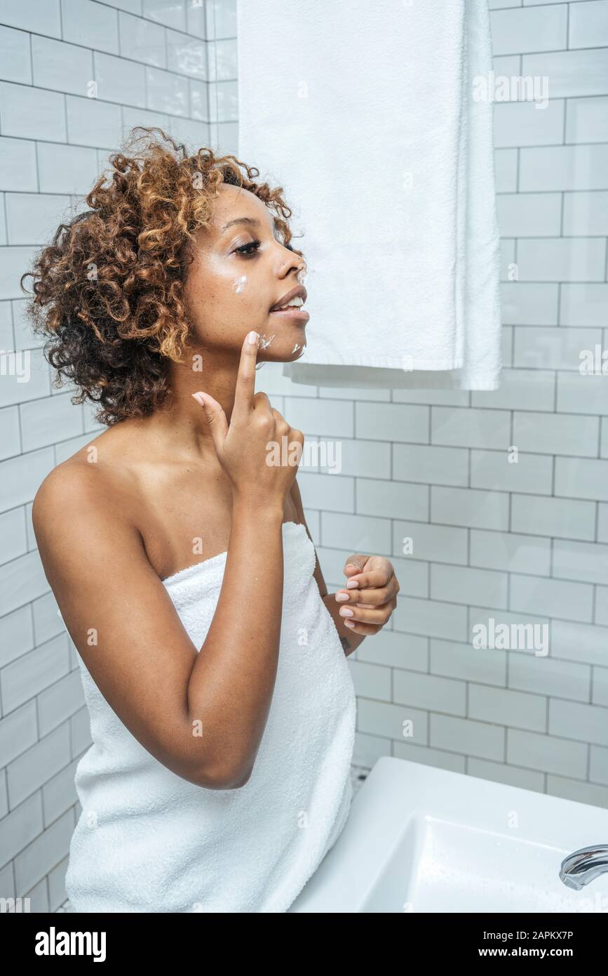 Junge Frau im Bad mit Gesichtscreme Stockfoto