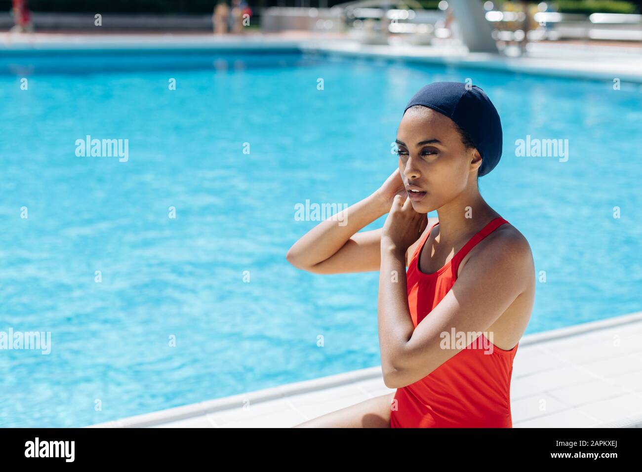 Portrait der jungen Frau, die am Pool eine Schwimmkappe aufsetzt Stockfoto