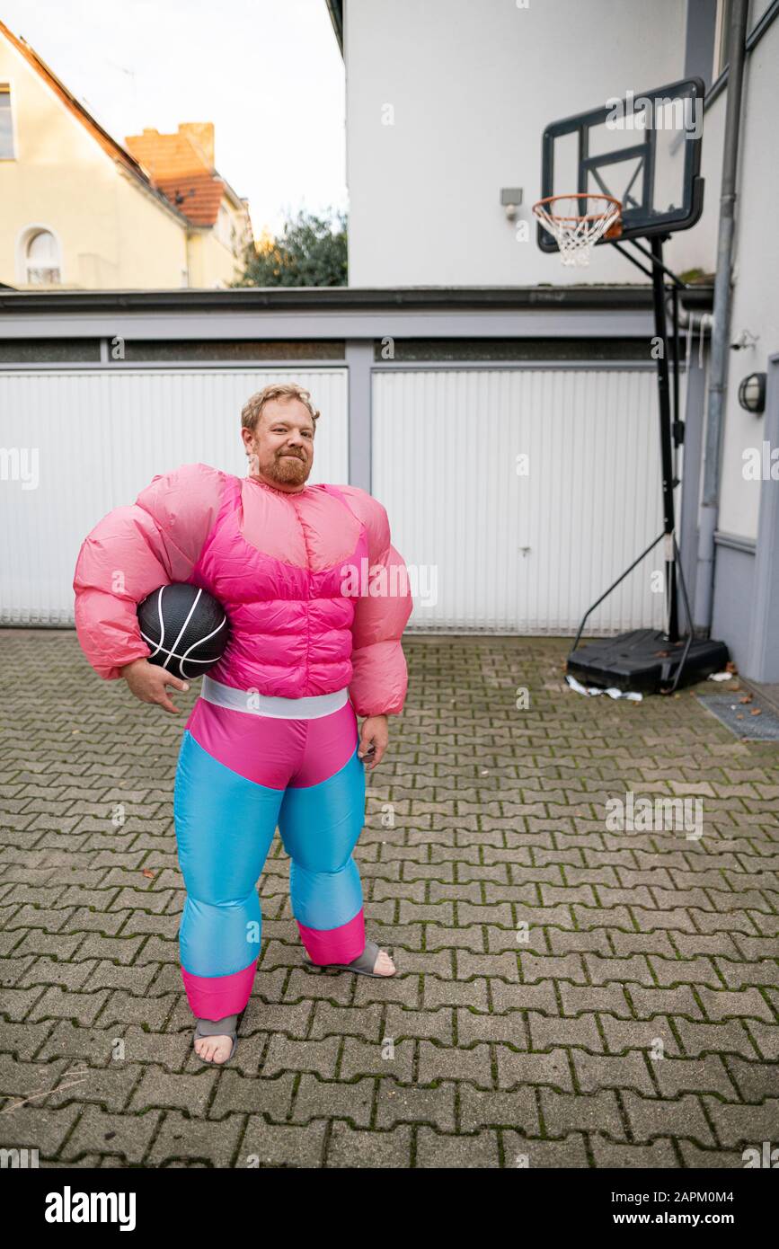 Porträt eines Mannes mit Basketball mit pinkfarbenem Bodybuilder-Kostüm Stockfoto