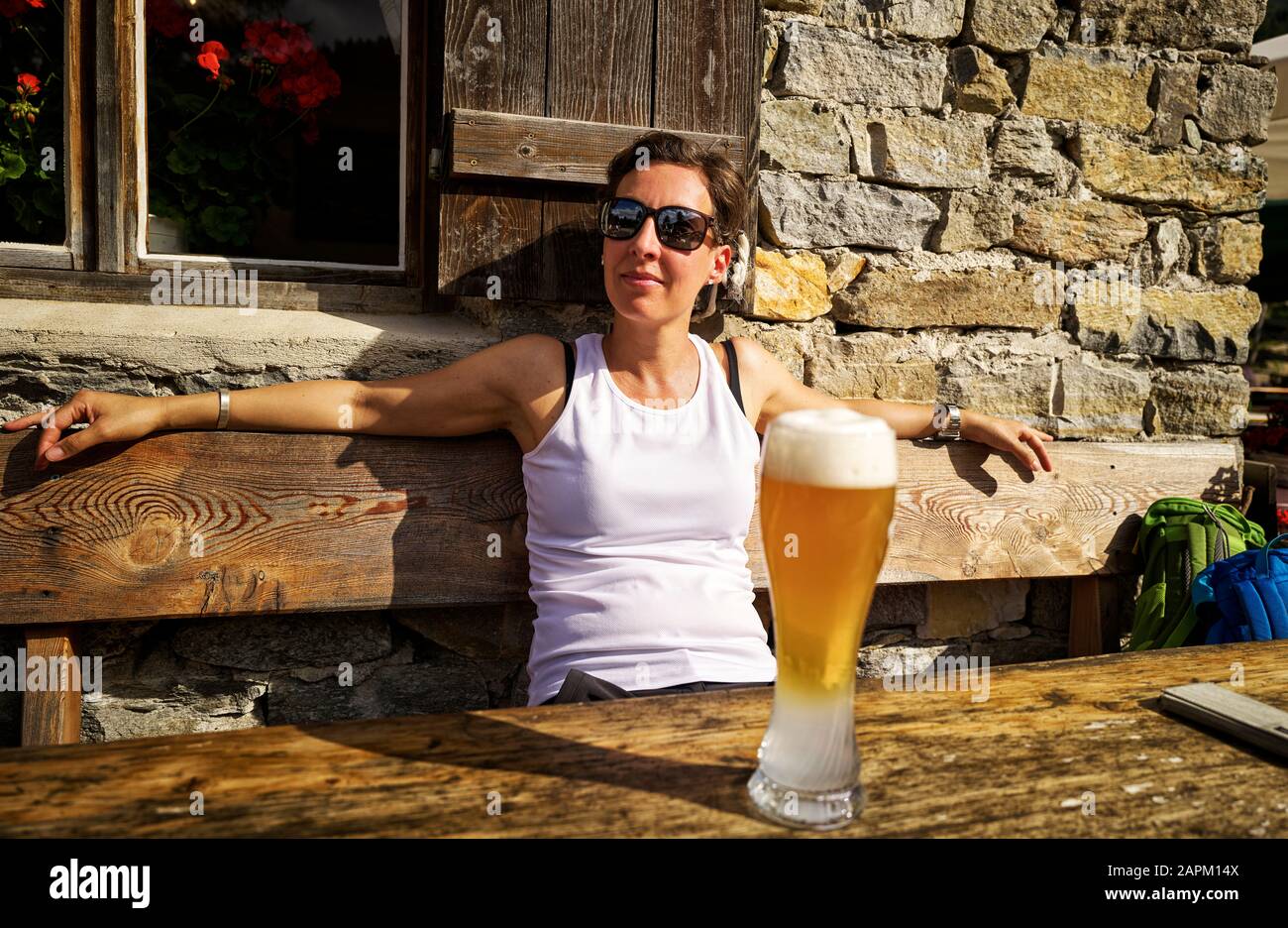 Sonnenschein und Weizenbier genießen Frau in einer Berghütte, Passeiertal, Südtirol, Italien Stockfoto