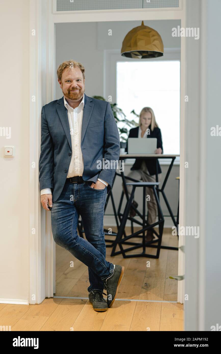 Porträt eines Casual Businessman im Büro mit Geschäftsfrau im Hintergrund Stockfoto