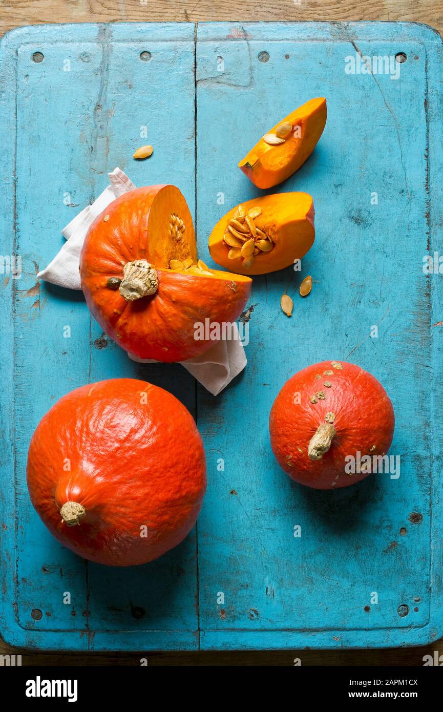 Rote kuri-Squashes (Cucurbita maxima) auf blauem Schneidebrett Stockfoto