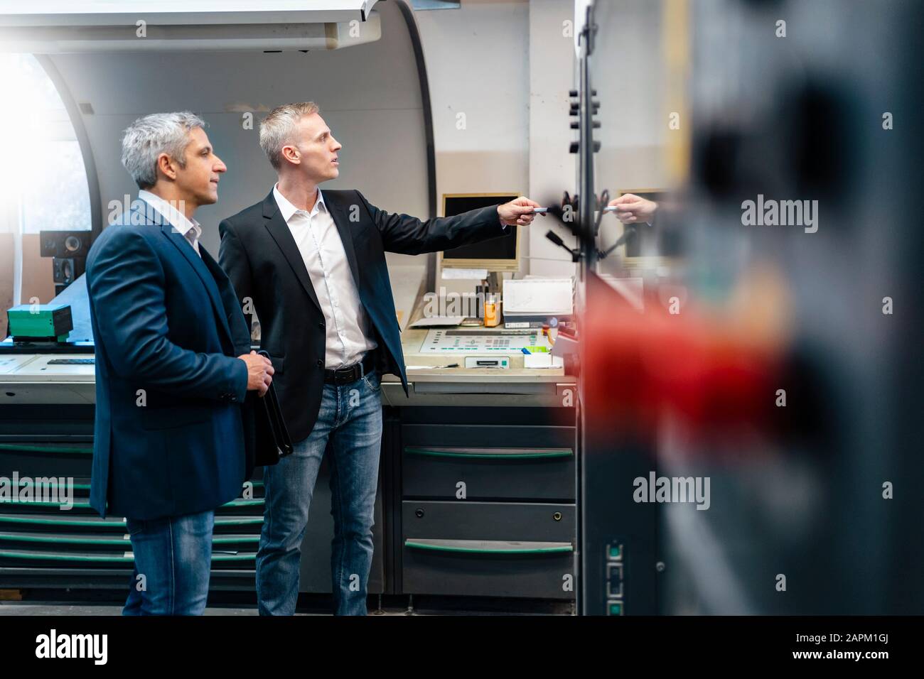 Zwei Geschäftsleute an einer Maschine in einer Fabrik Stockfoto