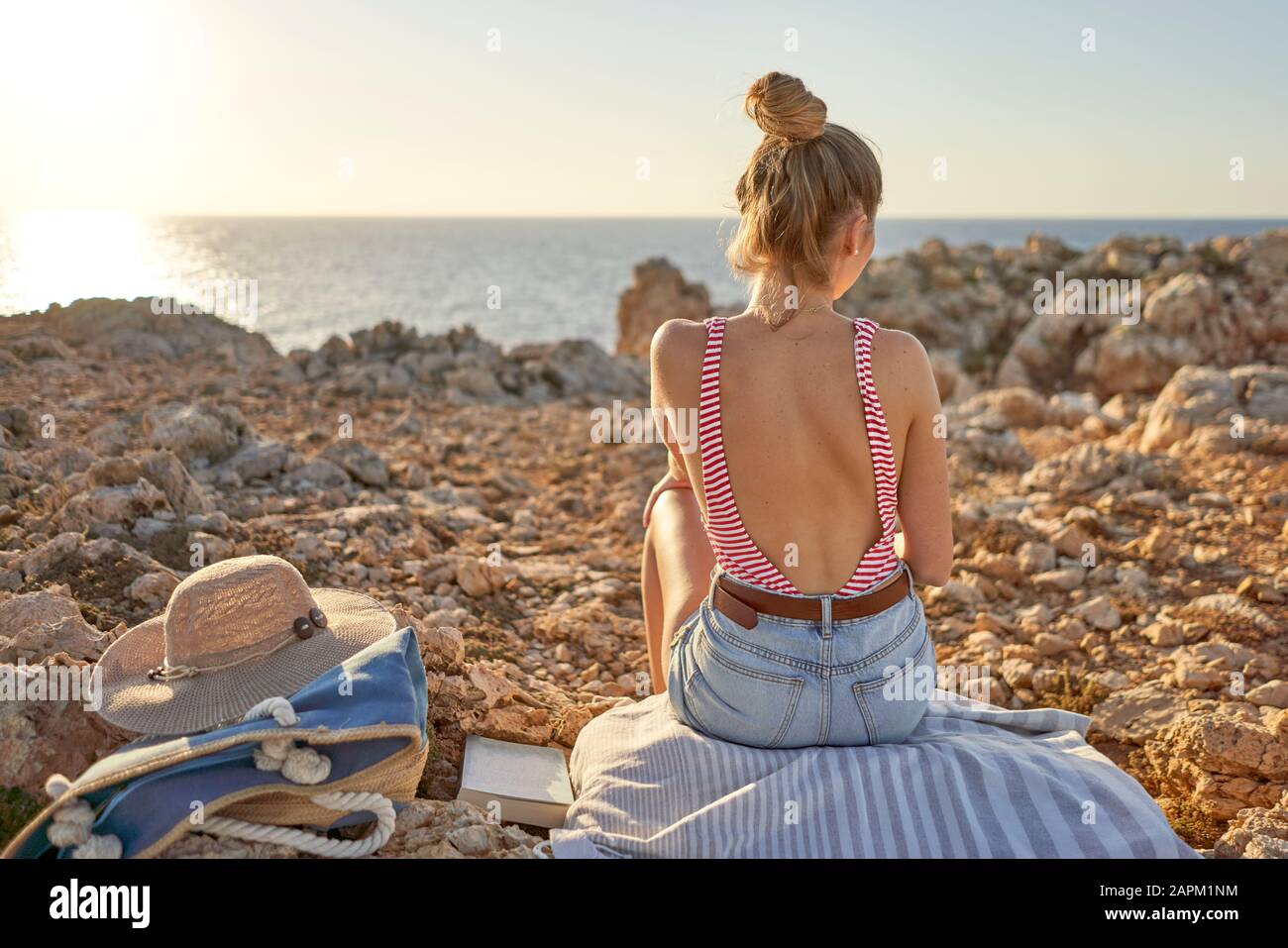 Junge Frau am felsigen Strand, entspannend, Menorca, Spanien Stockfoto