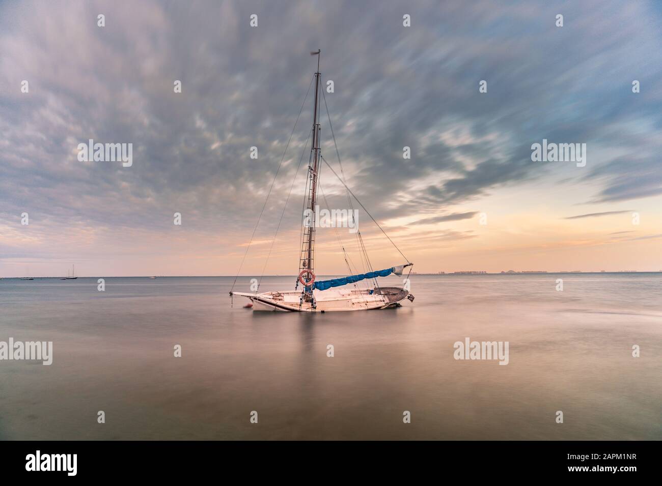 Spanien, Murcia, Santiago de la Ribera, verlassenes Segelboot auf ruhigem Meer bei Sonnenuntergang Stockfoto
