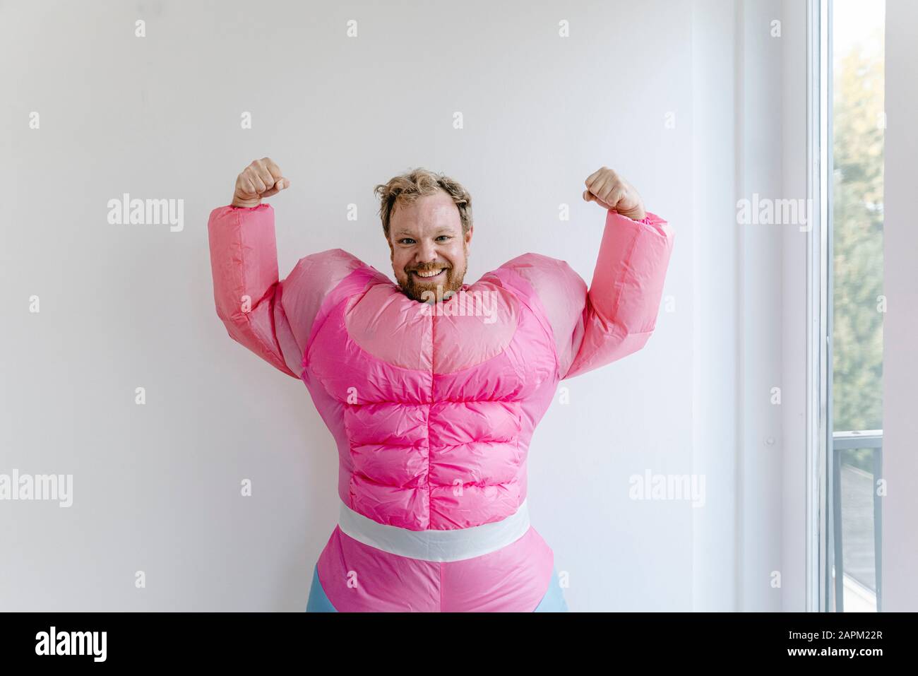 Stolzer Mann mit pinkfarbenem Bodybuilder-Kostüm, der seine Muskeln beugt Stockfoto