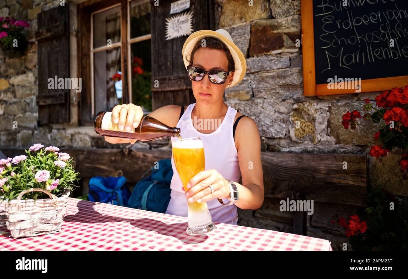 Frau, die in einer Berghütte, Passeiertal, in Südtirol, Italien, ein Weizenbier gießt Stockfoto