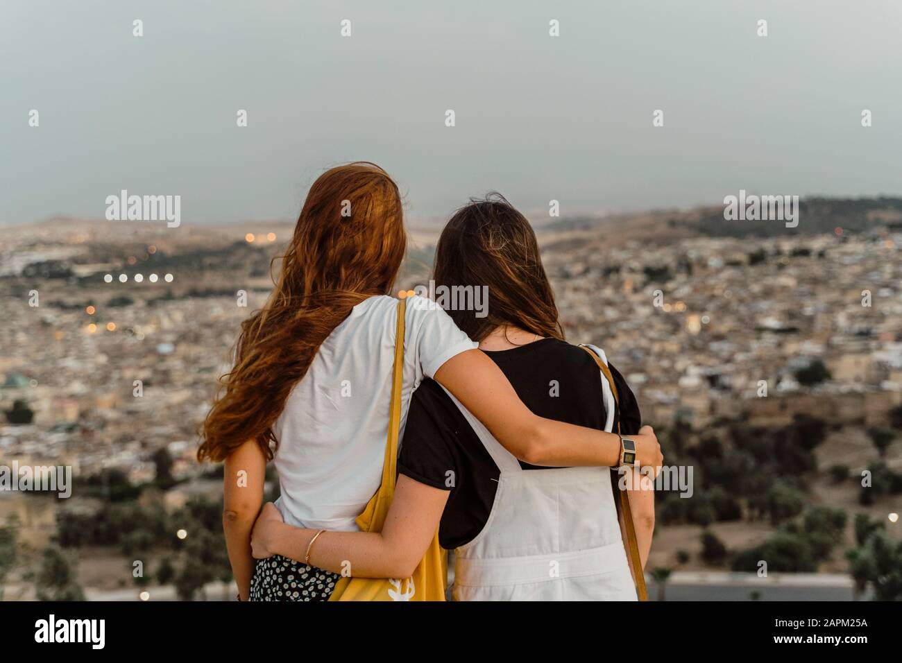 Rückblick auf zwei beste Freunde, die abends Arm in Arm mit Blick auf die Stadt genießen, Fez, Marokko Stockfoto