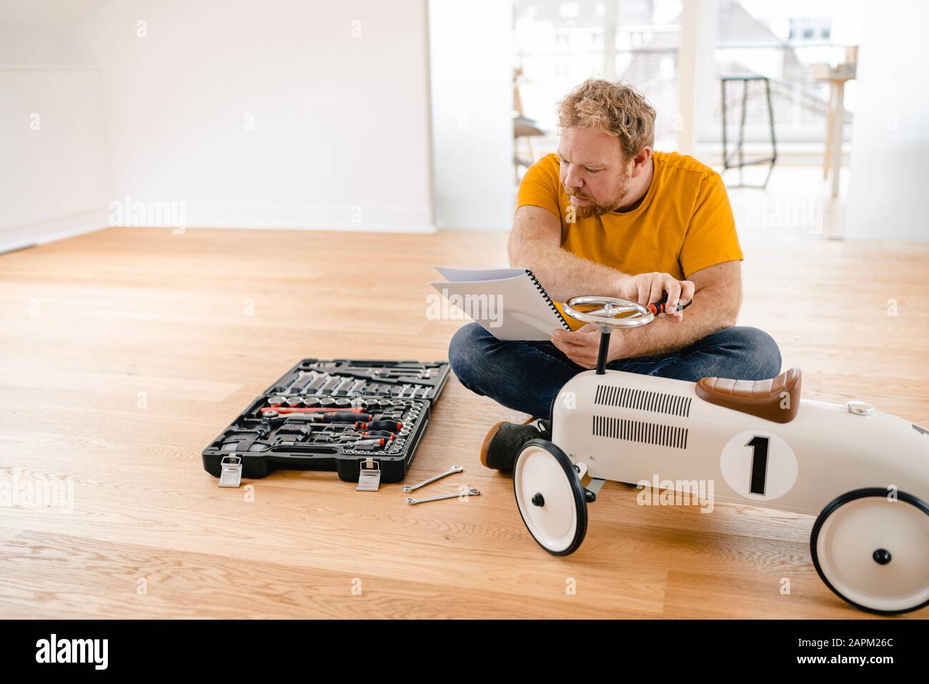 Mann, der Spielzeugauto zusammenbaut, Anweisungen lesen Stockfoto
