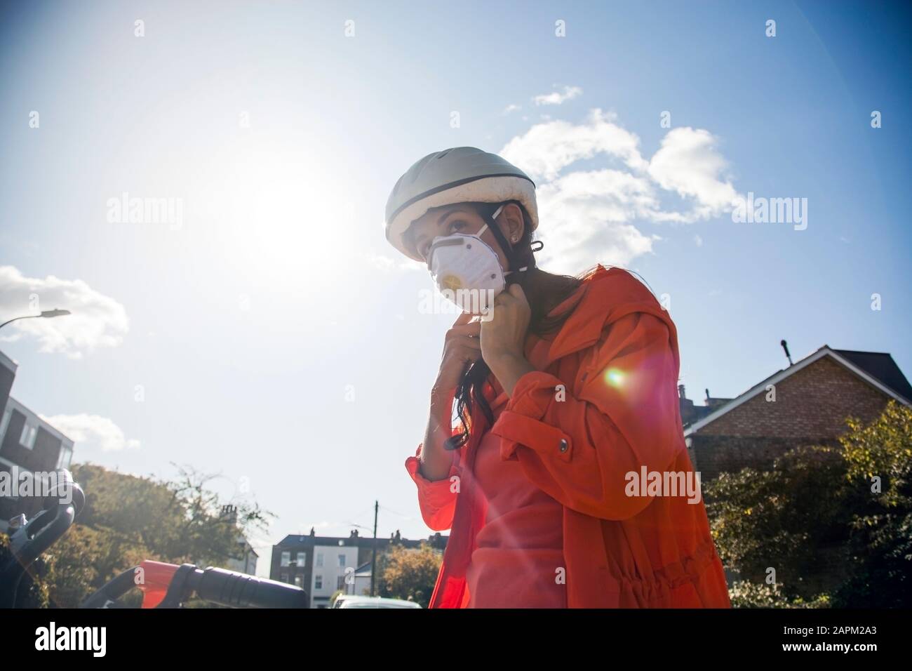 Frau trägt Gesichtsmaske und stellt ihren Radhelm m ein Stockfoto