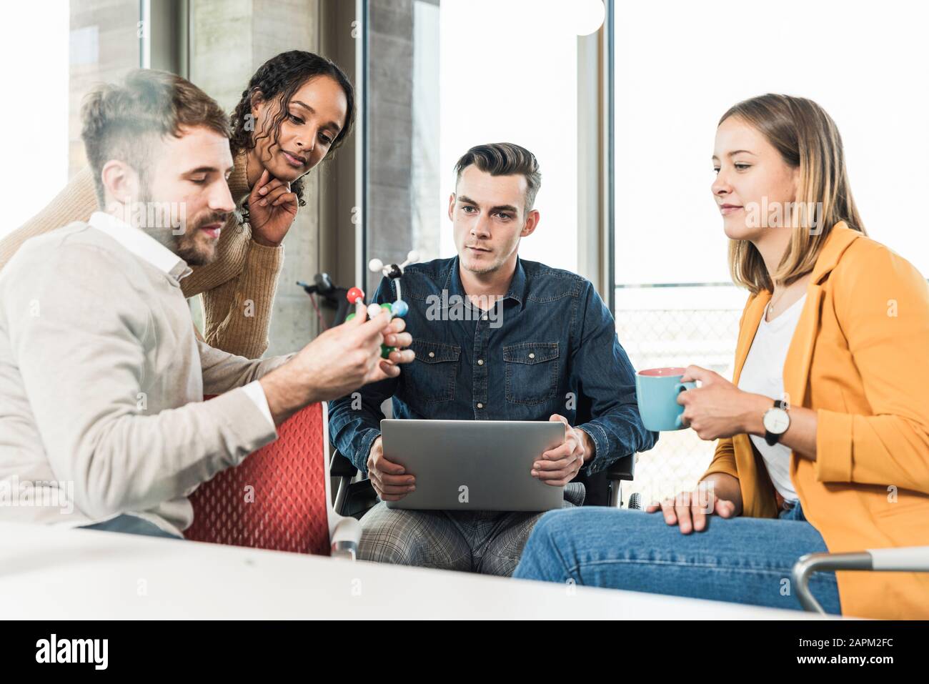 Junge Geschäftsleute mit Laptop und Atommodell haben ein Treffen im Büro Stockfoto