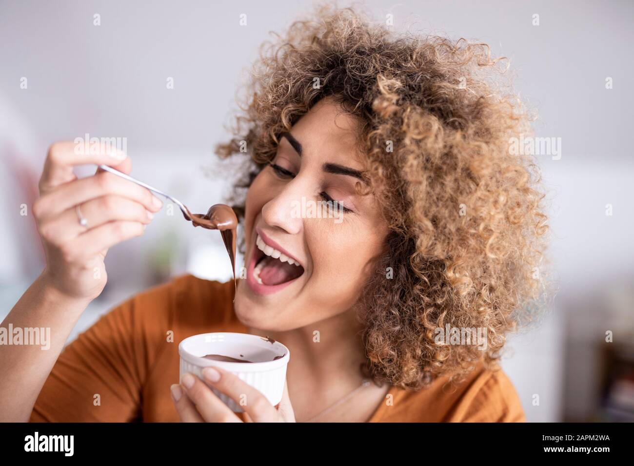 Portrait einer glücklichen Frau, die Schokolade isst, breitete sich zu Hause aus Stockfoto