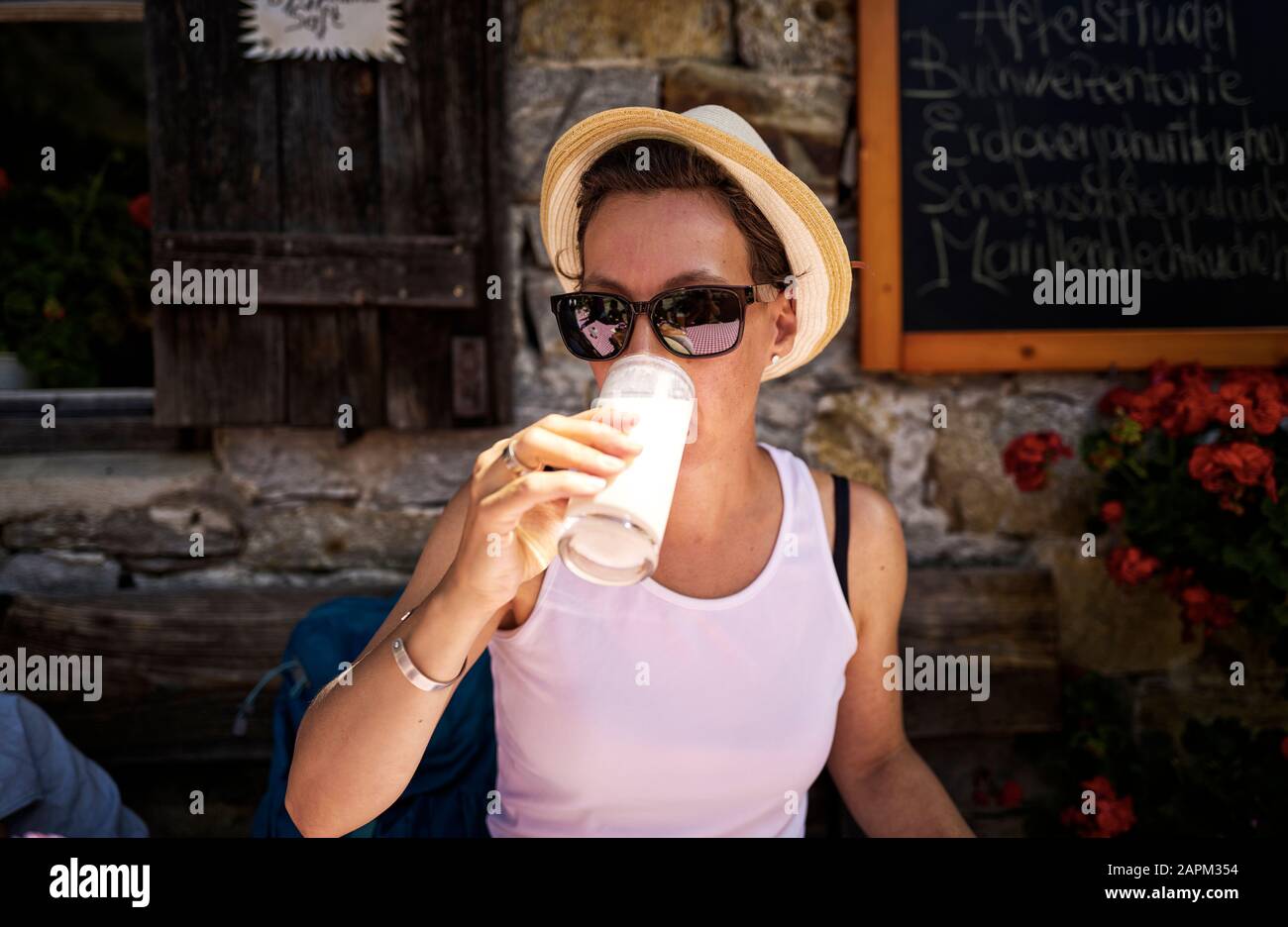 Frau, die ein Glas Buttermilch in einer Berghütte, Passeiertal, Südtirol, Italien genießt Stockfoto