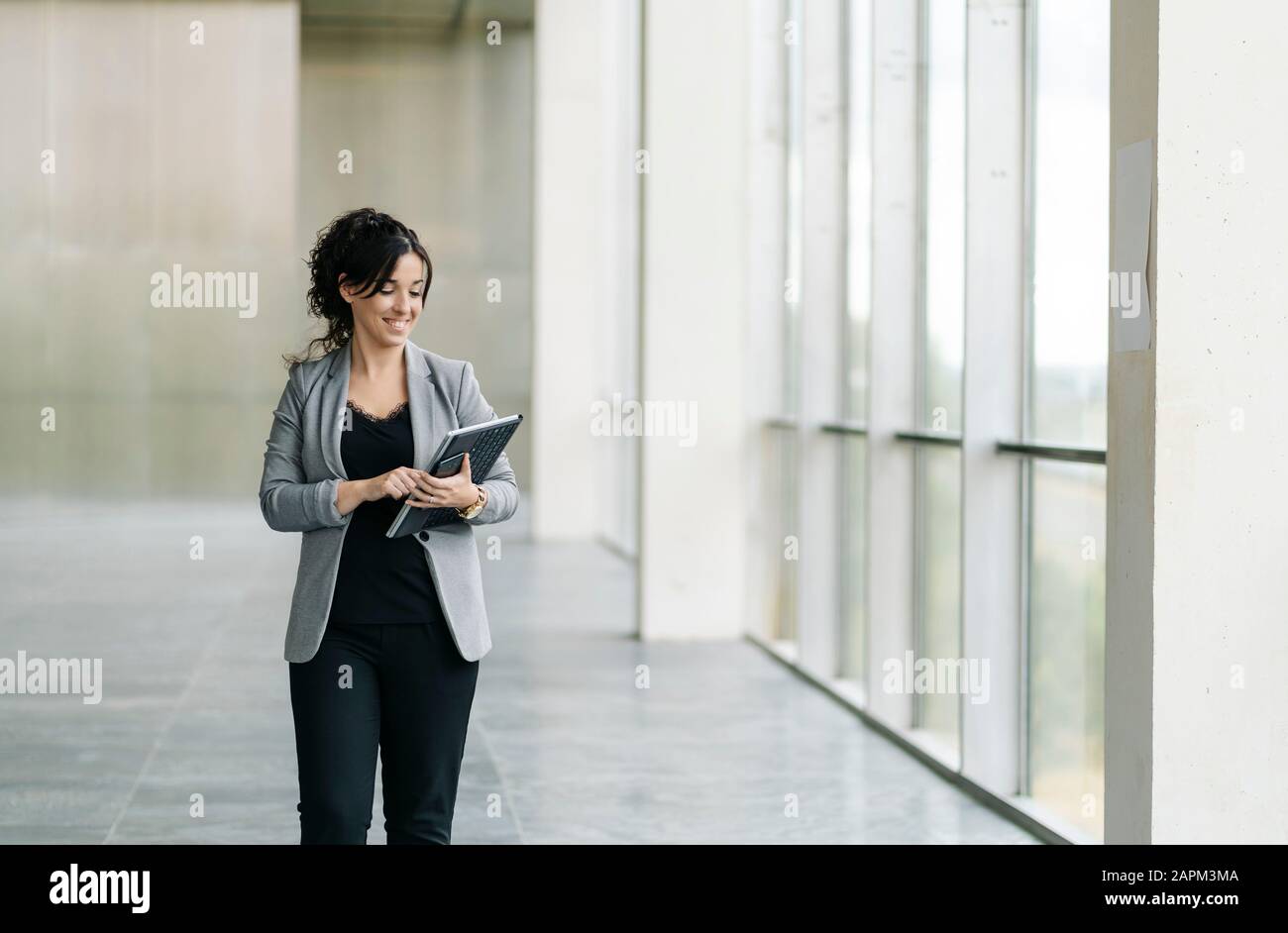 Lächelnde Geschäftsfrau mit Tablet am Fenster Stockfoto