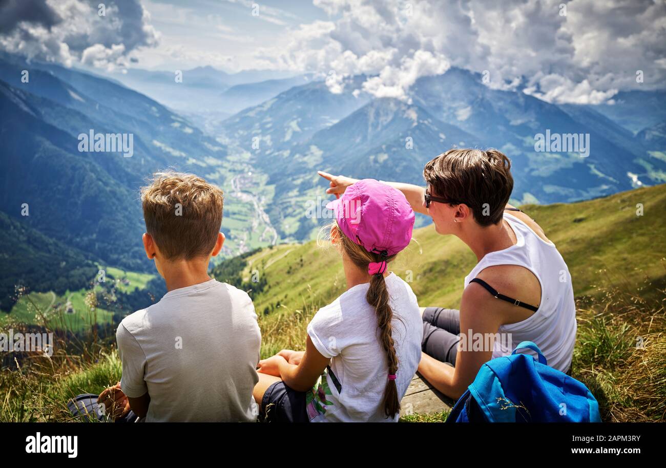 Mutter mit zwei Kindern, die eine Pause vom Wandern in der Alpenlandschaft, Passeiertal, Südtirol, Italien, einlegen Stockfoto
