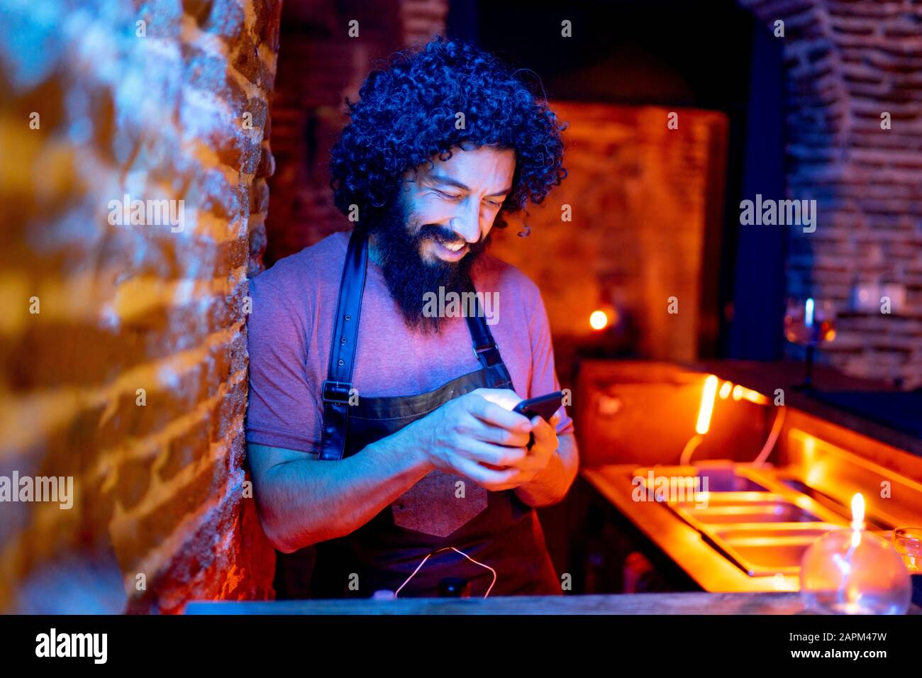 Junger Mann, der in der Bar arbeitet und Smartphone verwendet Stockfoto